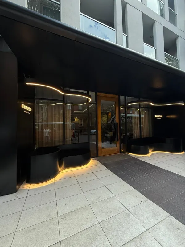 La fachada negra del hotel con su banco iluminado