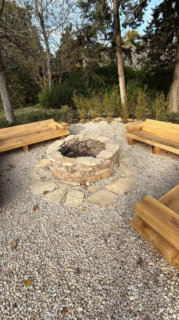 Fogonero de piedra con bancos de madera bajo los árboles, en una visita postventa