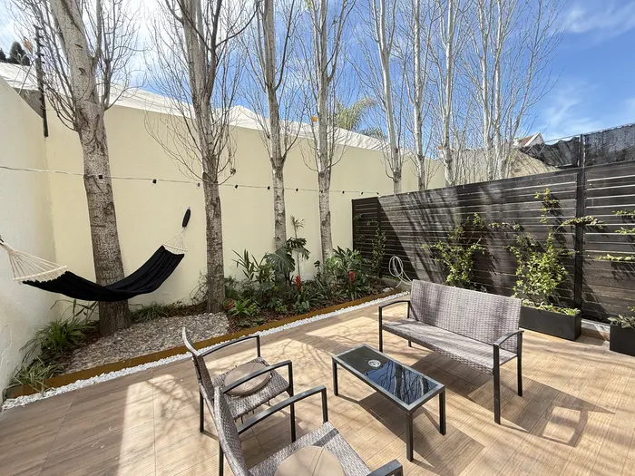 Patio parquizado con álamos, canteros de piedra y deck terminado